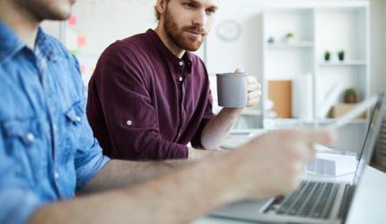 SEO specialist sat with client holding a cup of coffee checking client's website